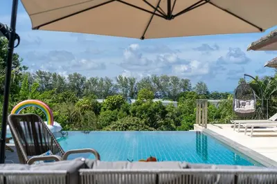 a swimming pool with chairs and an umbrella at \u5c71\u6d77\u306e\u5922 1600\u5e73\u8c6a\u534e\u79c1\u4eba\u6cf3\u6c60\u522b\u5885 15m\u8d85\u5927\u6cf3\u6c60 \u6b65\u884c\u6d77\u8fb9 \u514d\u8d39\u65e9\u9910 \u4f63\u4eba in Phuket Town