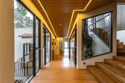 a hallway of a house with wood floors and windows at Sinae Residence in Ban Lo Ti Pa (1)