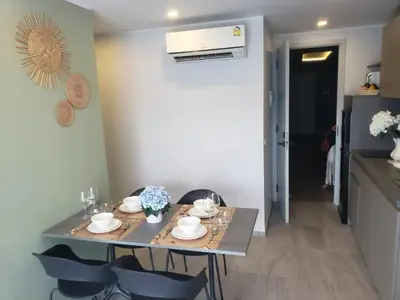a table in a room with chairs and a kitchen at Chalong Pier apartement in Phuket Town
