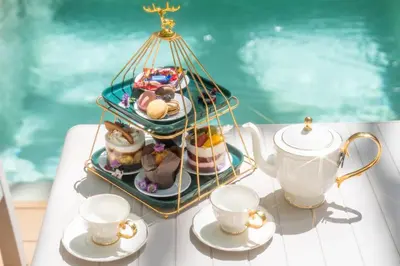 a table with a tray of desserts and tea cups at Timber Society Boutique Hideaway in Phuket Town