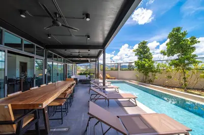 an outdoor patio with tables and chairs next to a swimming pool at BangTao 6-bedroom villa 18 meters, competition-grade swimming pool, industrial style design aesthetic, gaming and entertainment floor, suitable for family vacations and group gatherings in Bang Tao Beach