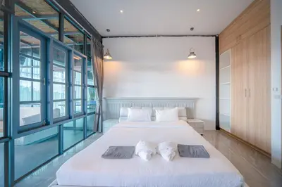 two beds in a room with large windows at BangTao 6-bedroom villa 18 meters, competition-grade swimming pool, industrial style design aesthetic, gaming and entertainment floor, suitable for family vacations and group gatherings in Bang Tao Beach