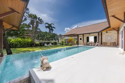 a teddy bear sitting on a bench next to a swimming pool at Kokyang Estate by TropicLook in Nai Harn Beach