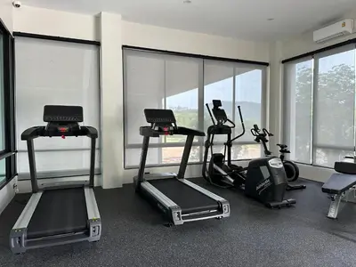 a gym with treadmills and ellipticals in a room with windows at Title Halo I Sea You Naiyang Pool Gym Sauna in Nai Yang Beach