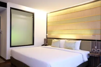 a bedroom with a large white bed with a large mirror at the beach height resort by sahana in Kata Beach