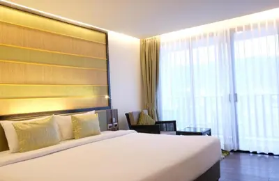 a hotel room with a bed and a large window at the beach height resort by sahana in Kata Beach