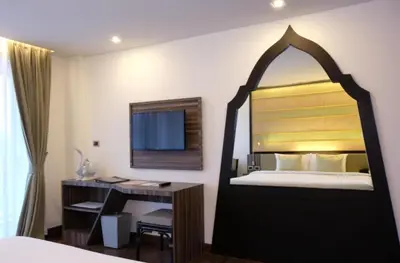 a hotel room with a bed with a desk and a mirror at the beach height resort by sahana in Kata Beach