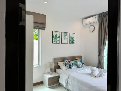 a bedroom with two beds and a clock on the wall at Kamala Evergreen Home in Kamala Beach