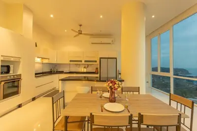 a kitchen and dining room with a wooden table and chairs at Best View In Phuket! 2 Living Rooms 4 BR #C80 in Karon Beach