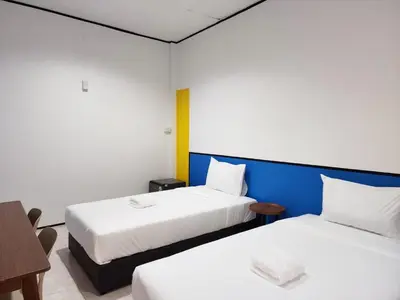 a hotel room with two beds and a table at RYB Hostel Phuket in Ban Lo Long