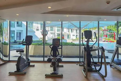 a gym with treadmills and exercise bikes in front of a window at La Vita Stylish apartment in 5 star hotel in Rawai Beach