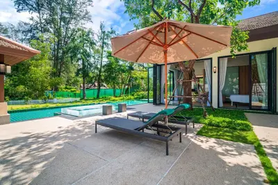 a patio with a chair and an umbrella and a pool at Banyan Tree Grand Residences by Banyan Living in Phuket Town