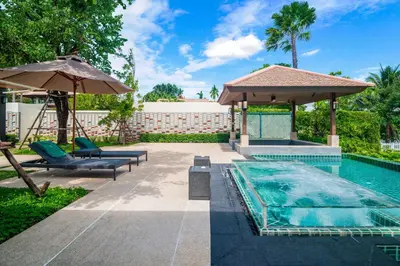 a backyard with a pool and an umbrella and chairs and a swimming pool at Banyan Tree Grand Residences by Banyan Living in Phuket Town