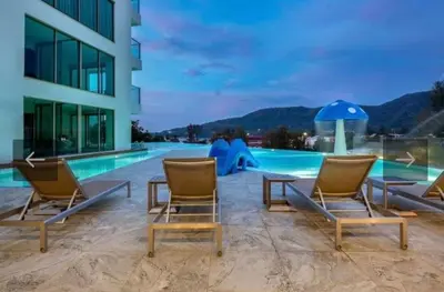 a group of chairs sitting next to a swimming pool at Oceana Kamala Stunning corner Suite Sea View in Kamala Beach