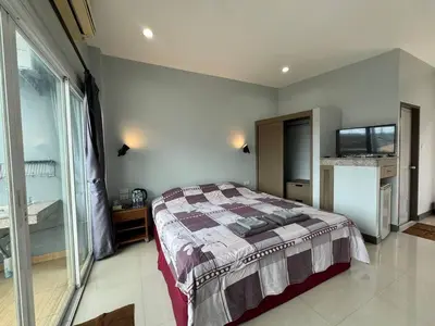 a bedroom with a bed and a large window at \u30d1\u30c8\u30f3\u30eb\u30fc\u30e07 in Patong Beach
