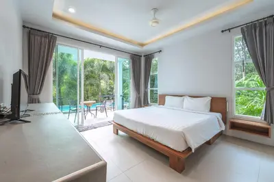 a bedroom with a bed and a tv and some windows at Little Kamala Hill in Kamala Beach