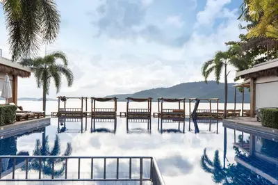 a swimming pool with chairs and a view of the ocean at Serenity Rawai by Destada in Rawai Beach