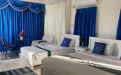 a bedroom with two beds and blue curtains at BOUTIQUE-VILLA with Suites & Rooms in Karon Beach