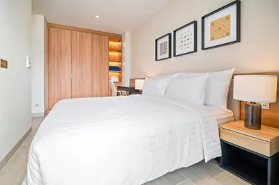 a bedroom with a large white bed and a lamp at Laguna Lakeside Residences by Banyan Living in Laguna Phuket