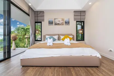 a bedroom with a large bed and large windows at patong hill villa 3 in Patong Beach