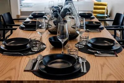 a long wooden table with black plates and wine glasses at 5BR Modern Luxury Pool Villa Patong TPSV140 in Patong Beach