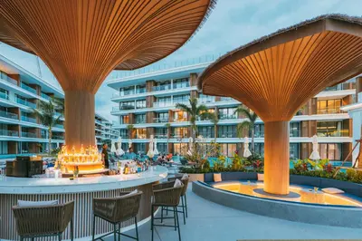 an outdoor patio with tables and chairs and a building at Kora Beach Resort Phuket in Bang Tao Beach