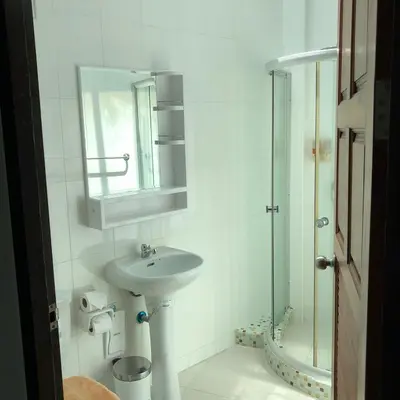 a white bathroom with a sink and a mirror at Pennapa Chalet in Chalong