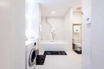 a white bathroom with a washing machine in it at Karon Beach Residence in Karon Beach