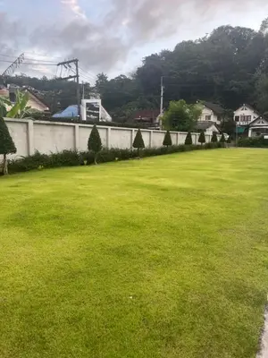 a large grass field with a wall and houses at Afiyath Residence in Kamala Beach