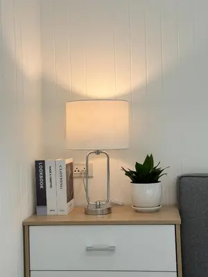 a lamp on a table with a plant and books at Sea Salt Casa Bang Tao in Ban Thalat Choeng Thale