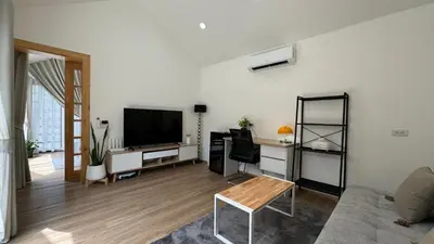 a living room with a couch and a tv at Sea Salt Casa Bang Tao in Ban Thalat Choeng Thale