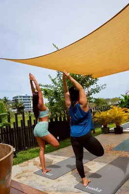 two women performing a yoga pose under a canopy at Sea Salt Casa Bang Tao in Ban Thalat Choeng Thale