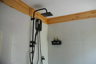 a shower in a bathroom with a shower head at Sea Salt Casa Bang Tao in Ban Thalat Choeng Thale
