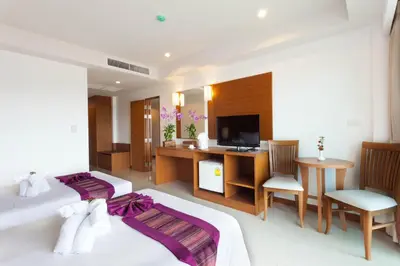a bedroom with a bed and a desk and a television at Rawai Princess Hotel in Rawai Beach