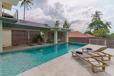 a swimming pool with two lounge chairs and a house at ANDAMAN Villa KOH YAO NOI in Ko Yao Noi