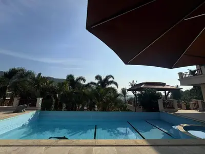 a swimming pool with an umbrella and palm trees at Kata Sea Cloud Villa\u534a\u5c71\u6d77\u666f\u72ec\u680b\u522b\u5885 in Kata Beach