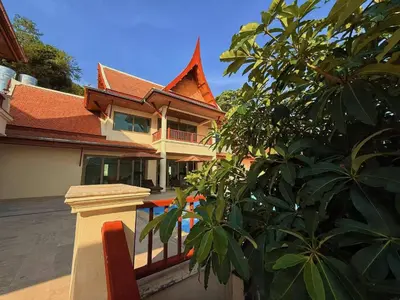 a house with a fence in front of a tree at Kata Sea Cloud Villa\u534a\u5c71\u6d77\u666f\u72ec\u680b\u522b\u5885 in Kata Beach