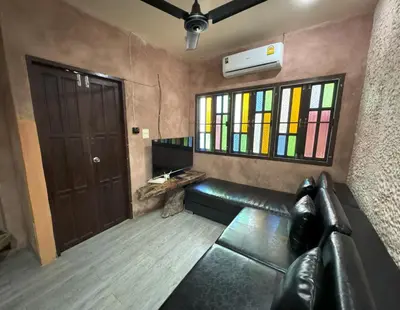 a room with a leather couch and stained glass windows at Kamala beach house 100m to the beach in Kamala Beach