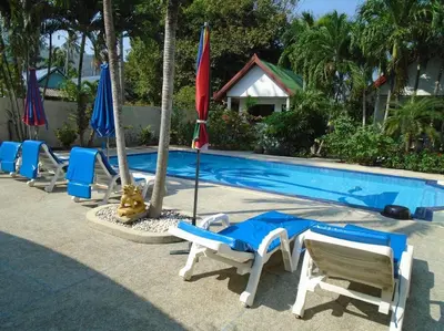 a group of chairs and umbrellas next to a swimming pool at Baan Coconut in Bang Tao Beach