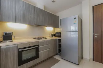 a kitchen with a white refrigerator and wooden cabinets at Laguna Parkside by Triple8 Asia in Laguna Phuket