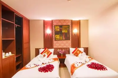 two beds in a room with red flowers on them at Patong Hemingways Hotel in Patong Beach