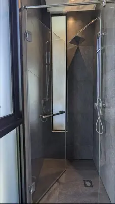 a shower with a glass door and a mirror at Charming Beachside Studio in Rawai Beach