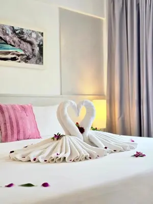 two white swans are forming a heart on a bed at ON Hotel Phuket - SHA in Karon Beach