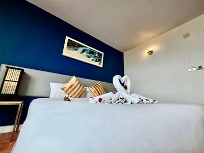 a bedroom with a large white bed with blue walls at ON Hotel Phuket - SHA in Karon Beach
