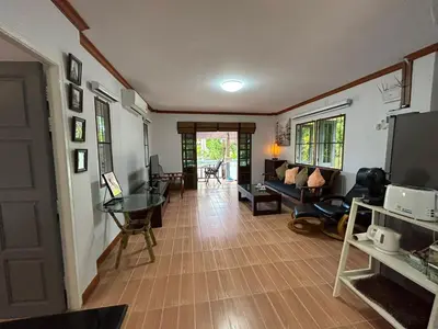 a living room with a couch and a television at Cozy Garden Cottage in Ao Nang