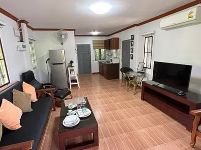 a living room with a couch and a flat screen tv at Cozy Garden Cottage in Ao Nang