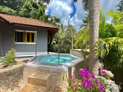 a swimming pool in a garden next to a house at Cozy Garden Cottage in Ao Nang