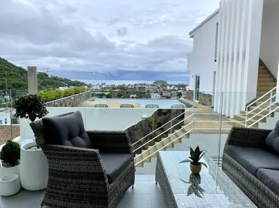 a balcony with wicker chairs and a glass table at Kata Ocean View 1 bedroom 50 m2 in Kata Beach