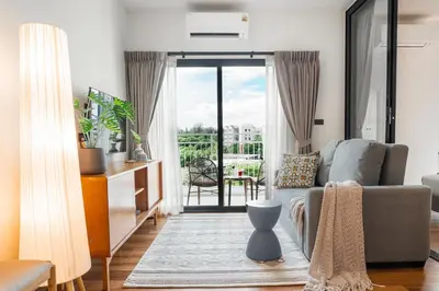 a living room with a couch and a balcony at Title Halo Andaman Coast Pool View Gym in Nai Yang Beach