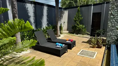 a patio with a black couch in a garden at Onyx Pool Villa in Phuket Town